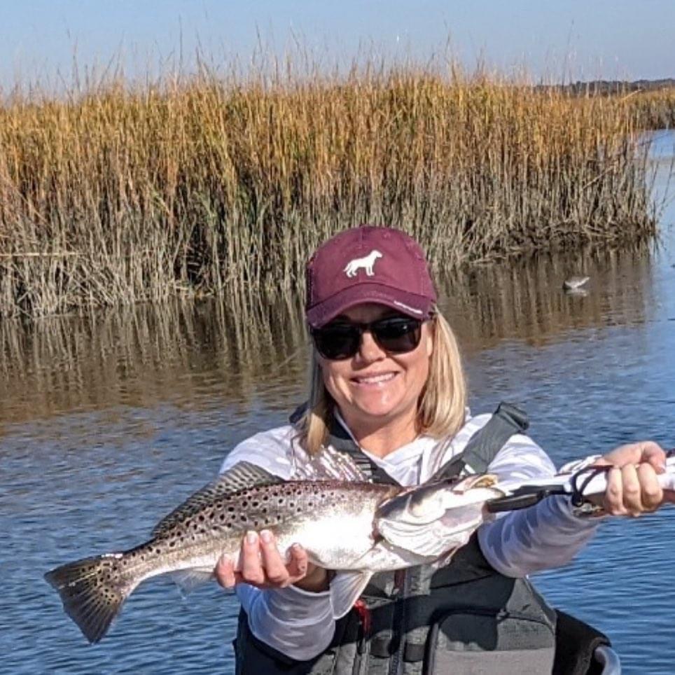 Angler with spotted seatrout in coastal marsh setting
