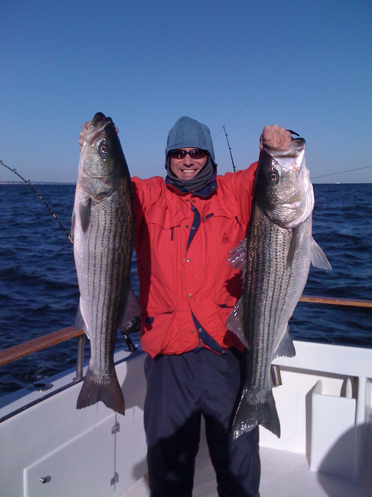 Angler with striped bass on beach at sunset with moonrise
