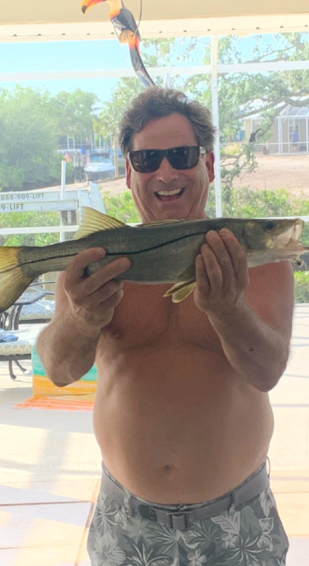 Young angler holding large striped bass on charter boat in winter