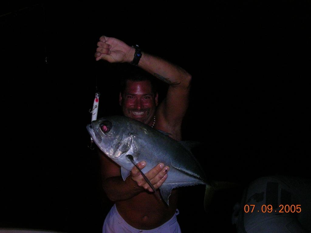 Angler with striped bass on beach during bass run with offshore boats