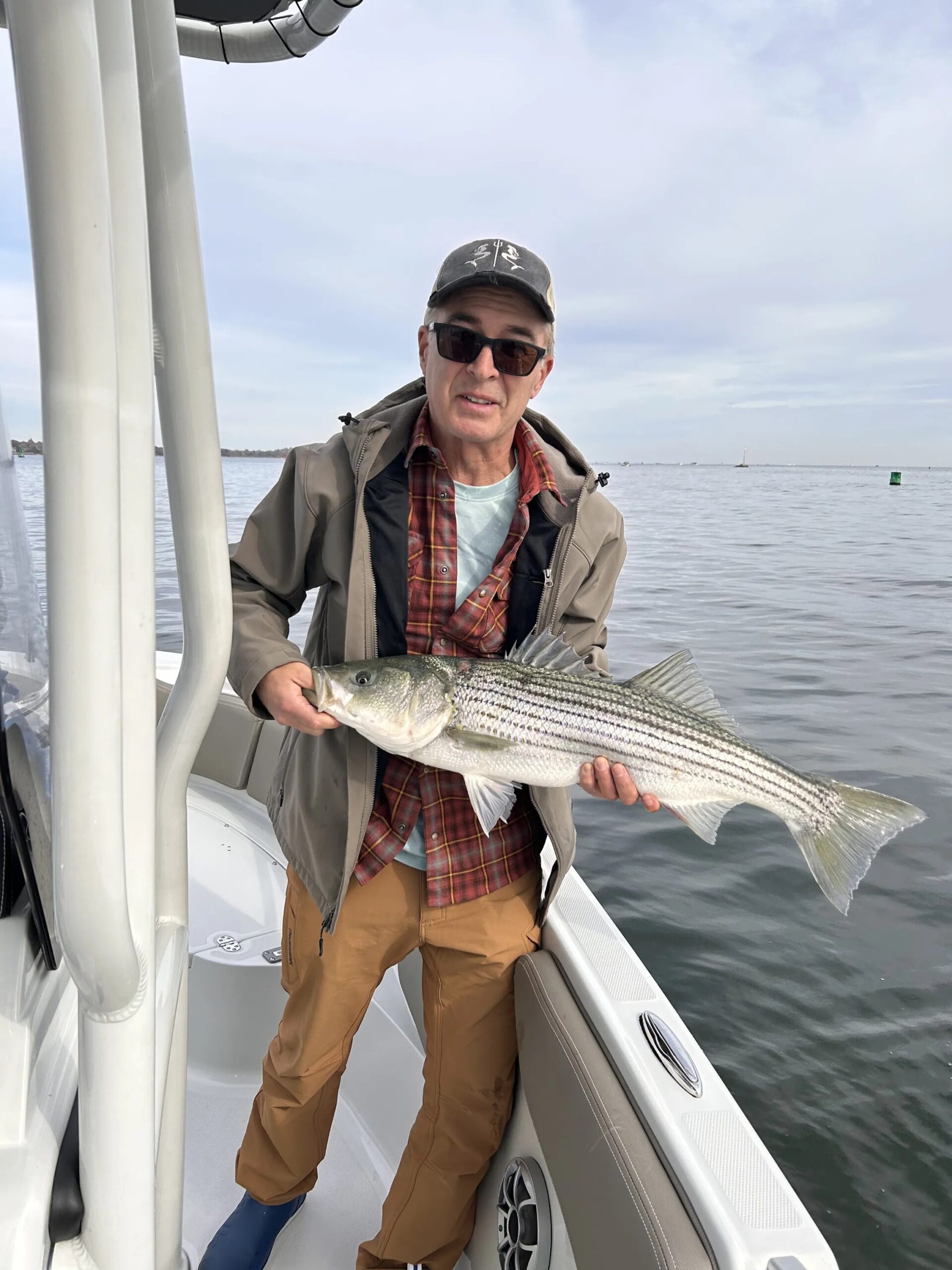 Angler holding sizable striped bass aboard center-console boat